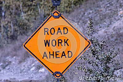 Battered sign warns ROAD WORK AHEAD in Glacier National Park Stock Photo