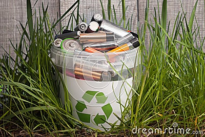 Battery recycle bin with old element on wood table in grass Stock Photo