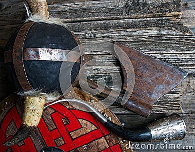 Ax horned helmet signal horn and shield covered with viking runes on rough wooden table top view Stock Photo