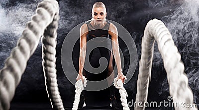 Battle ropes session. Attractive young fit and toned sportswoman working out in functional training gym doing exercise Stock Photo