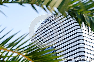 Courtyard by Marriott sign, in frame of palm leaves. Editorial Stock Photo