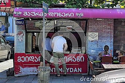 BATUMI, GEORGIA - JUNE 29, 2023: Unknown people buying shawarma at a small local shop in Batumi Editorial Stock Photo