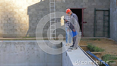 Bauarbeiter in einem Sturzhelm besprechen Bau-Gebäude-Häuser mit einem Pool stock footage Bauarbeiter in einem Sturzhelm besprechen Bau-Gebäude-Häuser mit einem Pool stock footage