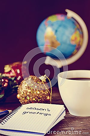 Bauble, cup of coffee, globe and text seasons greetings Stock Photo