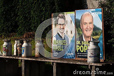 In Bavaria, CSU election posters stand in the countryside between old milk cans. The milk cans are made of metal and some are Editorial Stock Photo
