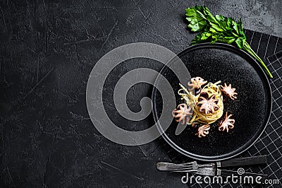 Bavette pasta with baby octopus. Black background. Top view. Space for text Stock Photo