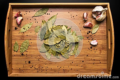 Bay leaf on a wooden background. Garlic and pepper in a pot. View from above. Seasoning flavoring for meat and food. Stock Photo