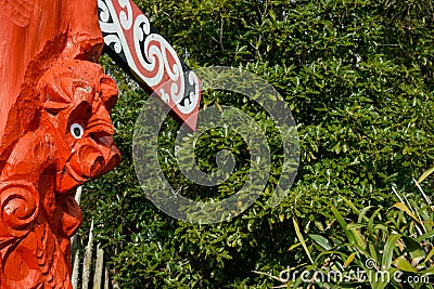 Red carved Maori totem closeup against greenery Editorial Stock Photo