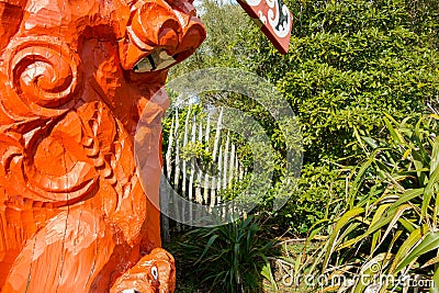 Red carved Maori totem closeup against greenery Editorial Stock Photo