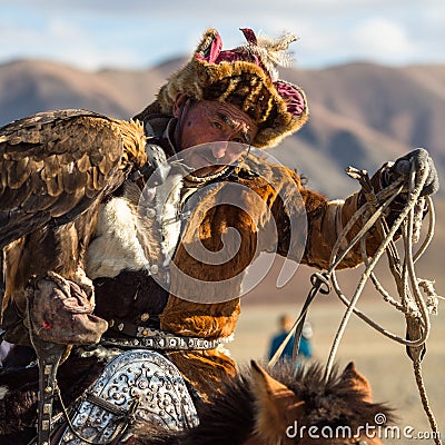 Kazakh Eagle Hunter at traditional clothing, on horseback while hunting to the hare holding a golden eagle Editorial Stock Photo