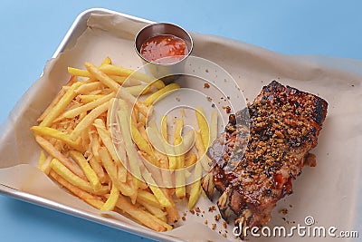 BBQ marinated spareribs and french fries with sauce. Barbecue cooked ribs with spice and sauce served on a metal tray Stock Photo