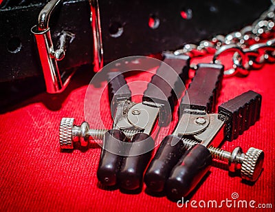 bdsm accessory human collar and accessory nipple clasp with metal chain on a red background close-up Stock Photo