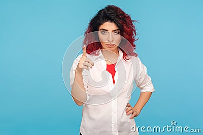 Be careful! Portrait of bossy displeased hipster woman with fancy red hair in white shirt holding finger up in admonishing gesture Stock Photo