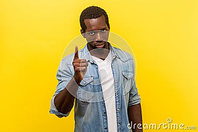 Be careful! Portrait of strict bossy young man standing with warning gesture. indoor studio shot isolated on yellow background Stock Photo