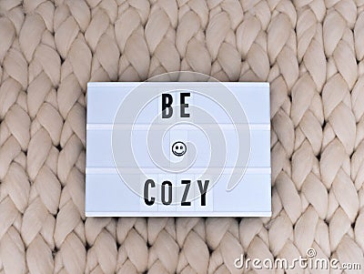 BE COZY word on lightbox on knit background. Cozy compozition. Knit background. Stock Photo