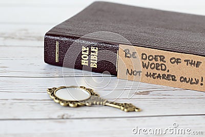 Be doer of the Word, not hearer only, handwritten verse with holy bible book and antique golden mirror on wooden table, a closeup Stock Photo