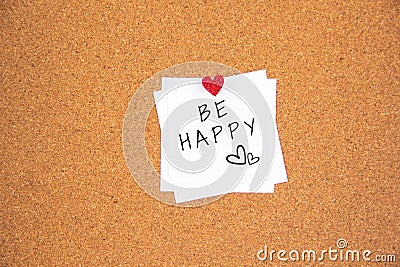 Be happy lettering on white paper pinned with red glowing heart-shaped thumbtack on cork board Stock Photo