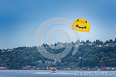 Be happy. Tourists parasailing with a happy face parachute on the coast of Seattle Editorial Stock Photo