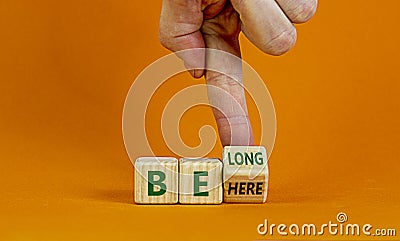 Be here belong symbol. Businessman changes words 'be here' to 'belong'. Stock Photo