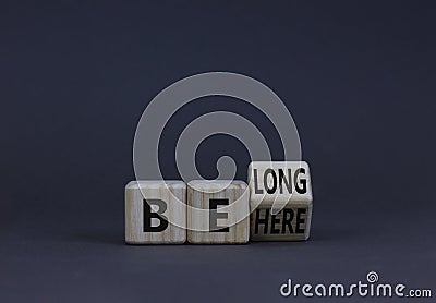 Be here belong symbol. Turned a wooden cube and changed concept words Be here to Belong. Beautiful grey background. Business, Stock Photo