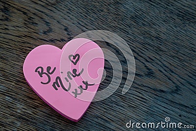 Be Mine hand wrote text on pink love heart with drawn hearts. On rustic wooden background. Love Valentines concept Stock Photo