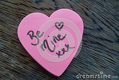 Be Mine hand wrote text on pink love heart with drawn hearts. On rustic wooden background. Love Valentines concept Stock Photo