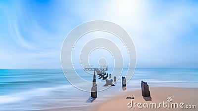 Beach with abandoned ruin pier over blue sea and sky Stock Photo