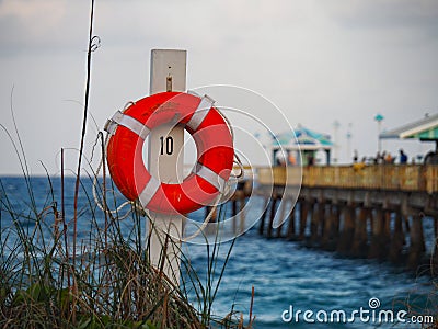 Beach access next to pier and lifeguard float hanging from pole Stock Photo