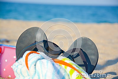 Beach accessories as sunglasses, slippers, towel, toys on sand Stock Photo