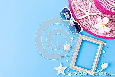 Beach accessories Picture Frame, sunglasses, flip flop, starfish beach hat and sea shell on bright pastel blue sky background for Stock Photo