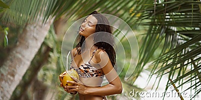 Beach Babe, Tanned Bikini-Clad Woman Enjoying Fresh Coconut Water on Sandy Shore Stock Photo