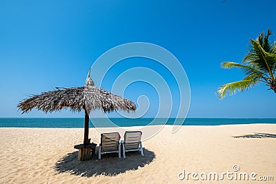 Beach chairs, umbrella and palms on sandy beach Stock Photo
