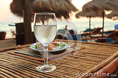 Beach evening on the sunset with glass of water and dinner Stock Photo