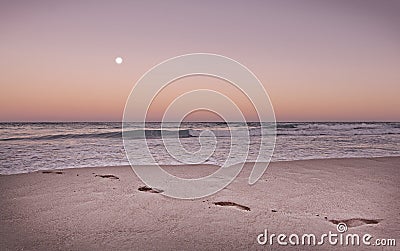 Beach footprints in orange dusk toned in Living Coral Stock Photo