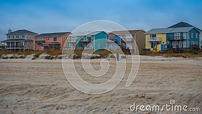 Beach houses with sand and grass and storm clouds Stock Photo