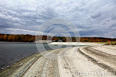 Beach landscape covered with light colored pebbles under gray cloudy sky Stock Photo