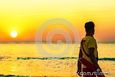 A beach lifeguard dressed in yellow - red uniform at the seasise during sunset in a beach of Dubai in the United Arab Emirates Stock Photo