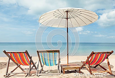 Beach lounge chairs under umbrella on beach. Stock Photo