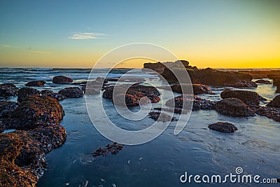 Beach during low tide. Amazing seascape. Stones covered by water. Sunset time. Golden hour. Slow shutter speed. Soft focus. Clear Stock Photo