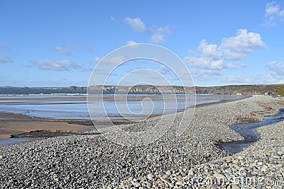 Sea view of beach with shingle and pebbles in foreground and cliffs in distance and sea centred. Stock Photo