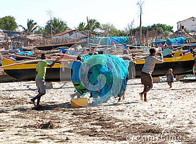 Beach with Malagasy canoes and fishermen with fishing nets, Madagascar Editorial Stock Photo