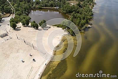 A beach near the city in springtime. Aerial view. Dirty river or lake. Few people. Quarantine Stock Photo