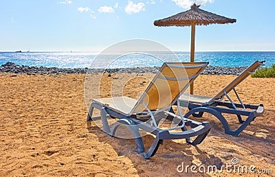 Beach with parasol and chaise longues by the sea Stock Photo