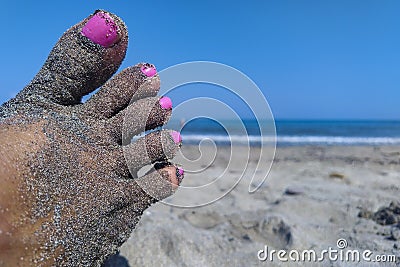 Beach sand on a woman feet with nails painted with nails polish Stock Photo