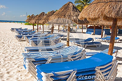 Beach shelters and chairs in the sun on a beach Stock Photo