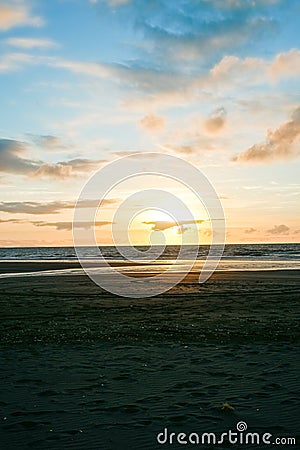 Beach in silhouette as sunsets on distant horizon Stock Photo