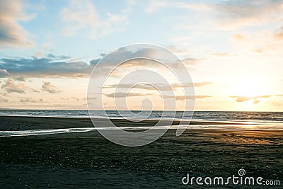 Beach in silhouette as sunsets on distant horizon over ocean Stock Photo