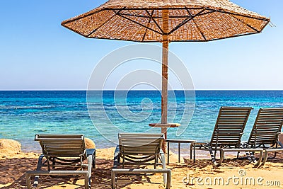 Beach with sunbeds and umbrellas against the background of the sea horizon. The bright blue sea. Snorkeling on the Red Sea in Stock Photo