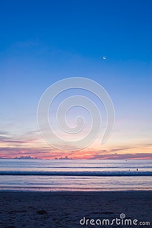 Beach sunset with a half-moon Stock Photo