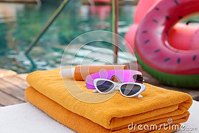 Beach towels, sunglasses and sunscreen on sunbed near outdoor swimming pool. Luxury resort Stock Photo